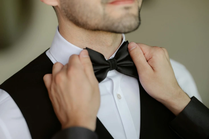 A man adjusts his bow tie.